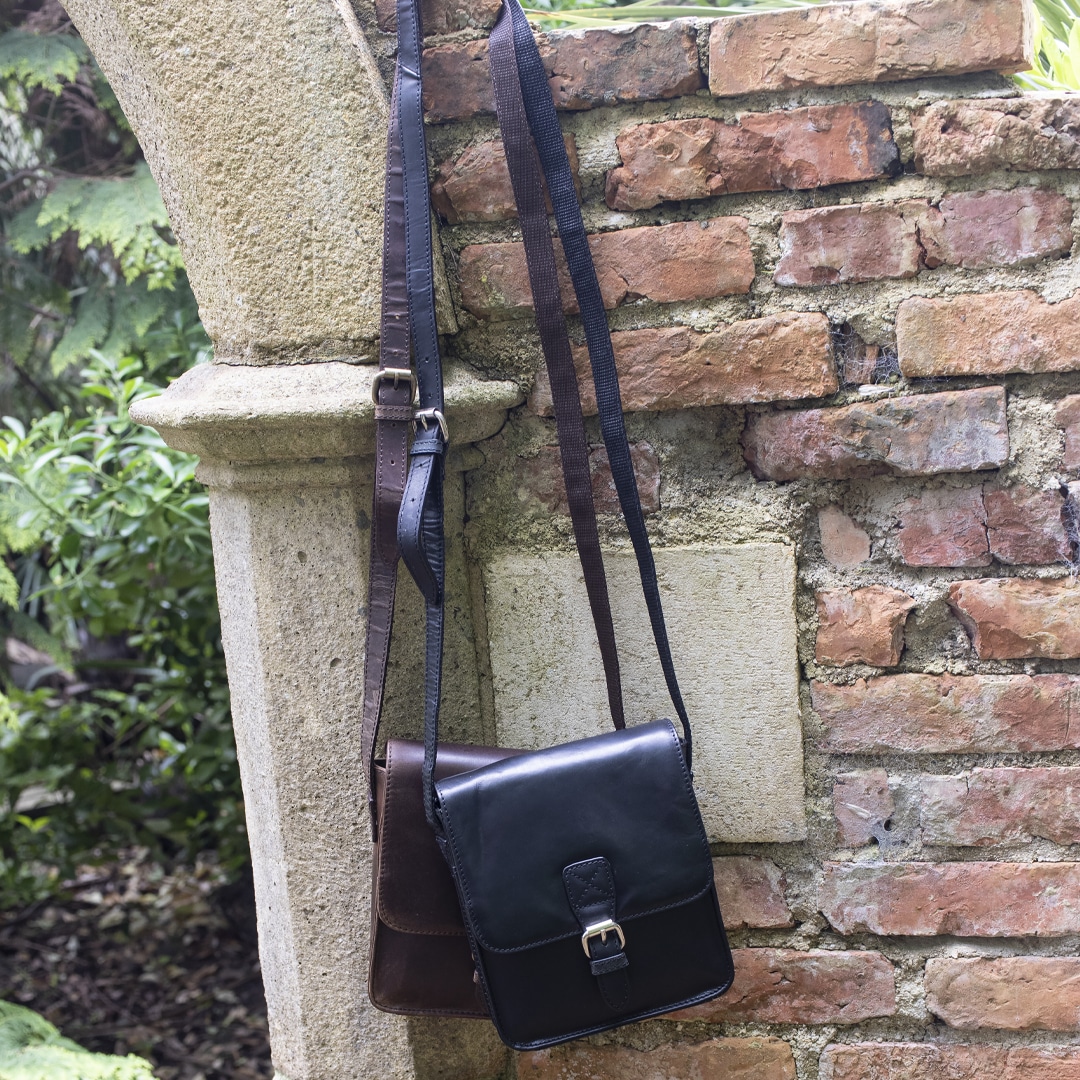 Leather Man Bags with a front buckle hanging on a wall