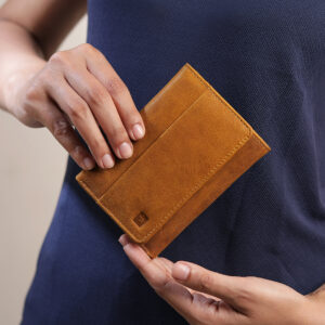 A person holding the yellow trifold wallet, demonstrating its compact size and easy portability, perfect for everyday use.