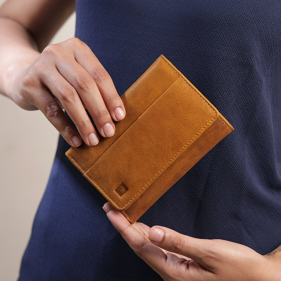 A person holding the yellow trifold wallet, demonstrating its compact size and easy portability, perfect for everyday use.