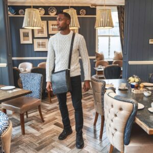 A gentleman with a small leather crossbody bag, adding a rustic charm to the ambiance of a country-style hotel.