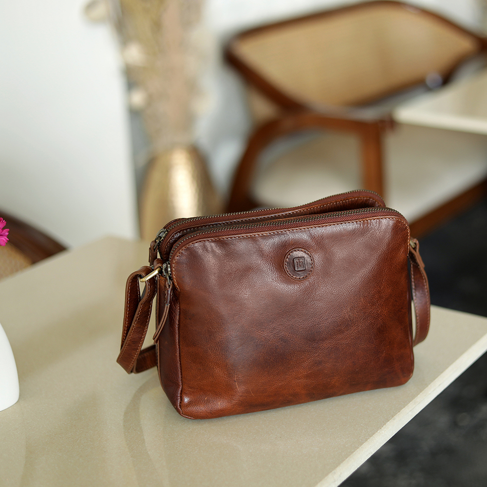 A spacious brown leather handbag for women, styled on a work desk