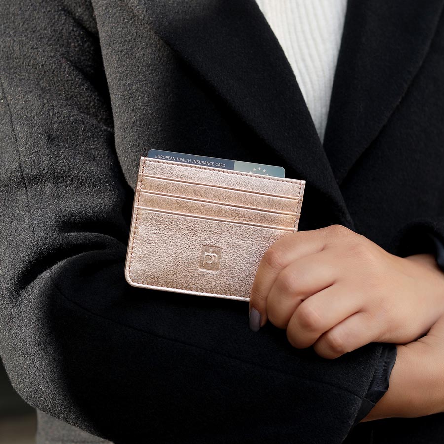 Rose Gold Personalised Leather Card Holder with RFID 04 Hand holding rose gold leather card holder against a black coat, showing neatly inserted cards.