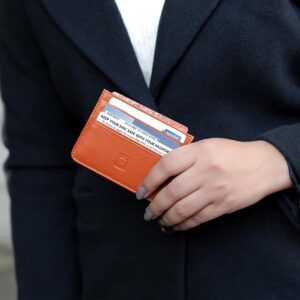 Tan Personalised Leather Card Holder with RFID 01 Woman holding a tan leather RFID card holder while wearing a black coat.
