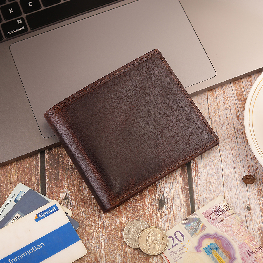 Wallet on desk with coins and cards Genuine leather bifold wallet for men, shown on a desk with banknotes and cards – a practical personalised gift idea.